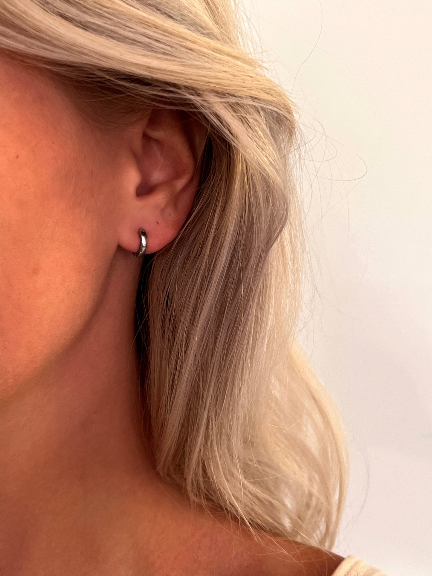 Close-up of the Orbis polished stainless steel hoop earrings with a rounded sculptural design.