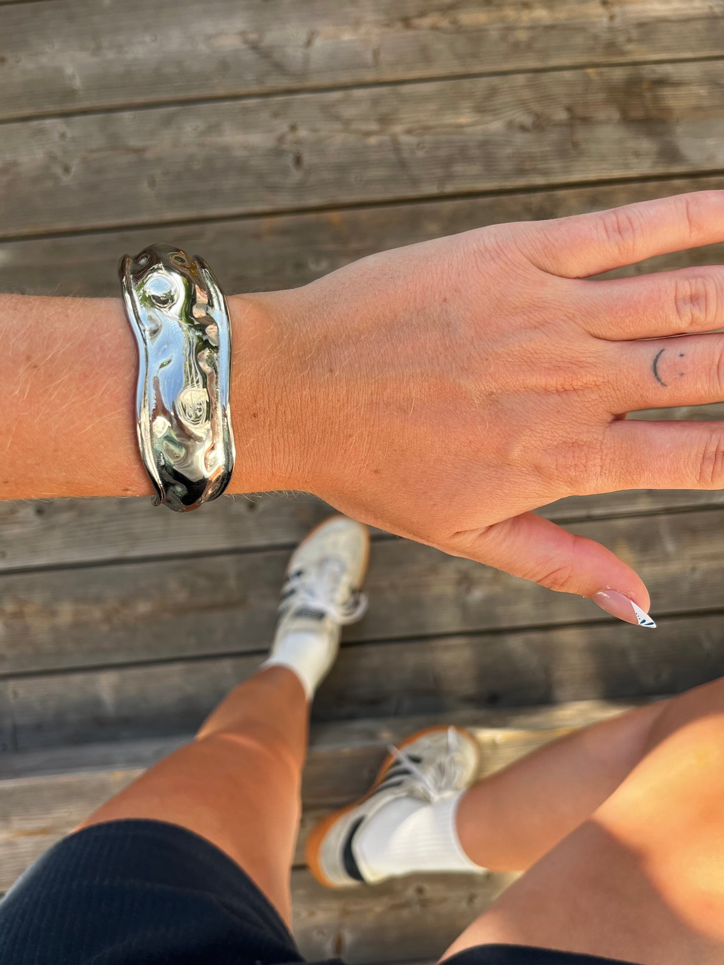 Closeup of THE TEXTURED BANGLE showing dented hammered texture, high-polish stainless steel unisex bracelet.