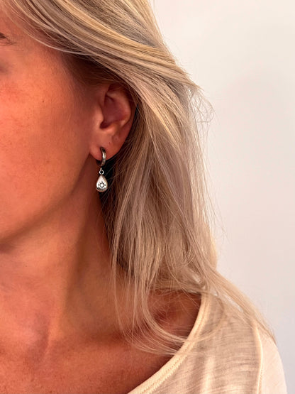 A person wearing the Aeva celestial star drop earrings in polished stainless steel.