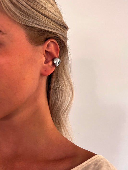 A person wearing the Cova sculptural dome ear cuff in polished stainless steel.