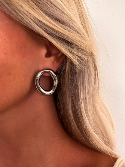Close-up of the Domena polished stainless steel oval hoop earrings with an open sculptural design.