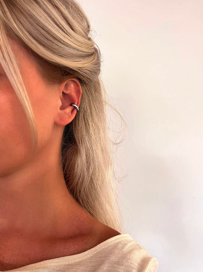 A person wearing the Forma minimalist ear cuff in polished stainless steel.