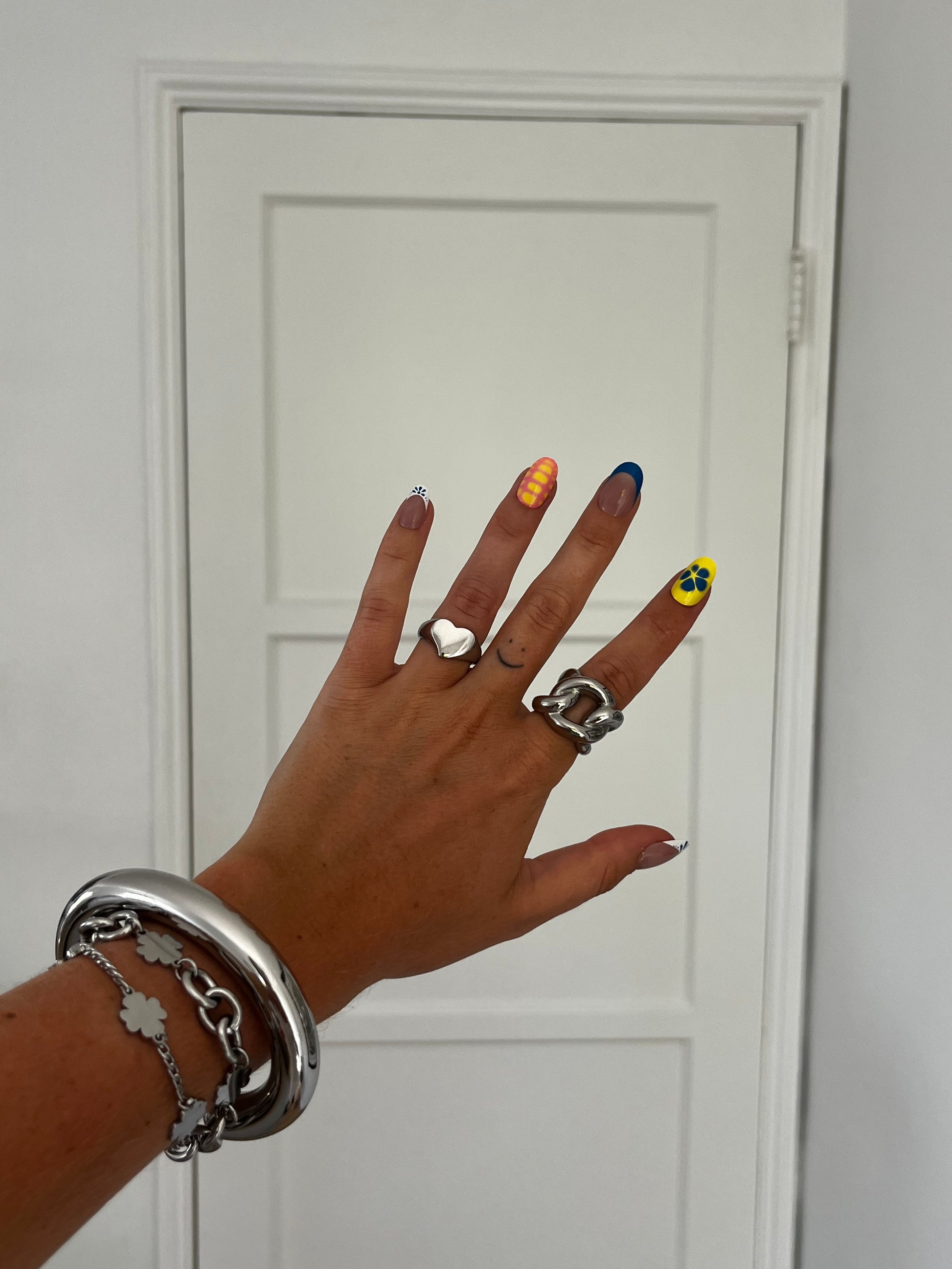 LOVIE silver heart-shaped ring stacked with other rings, versatile unisex statement jewelry.