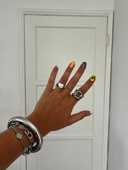 LOVIE silver heart-shaped ring stacked with other rings, versatile unisex statement jewelry.