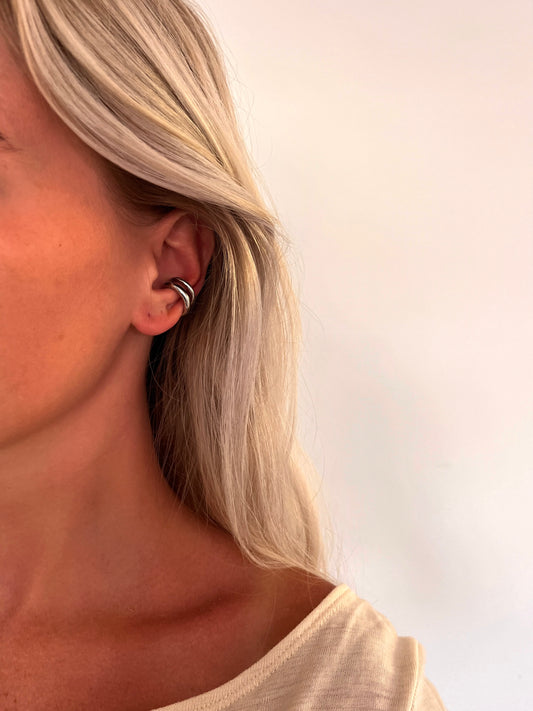 A person wearing the Nexo double-band ear cuff in polished stainless steel.