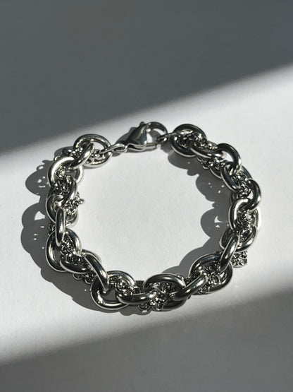 Closeup product image of chunky silver stainless steel intertwined chain bracelet showing texture and links.