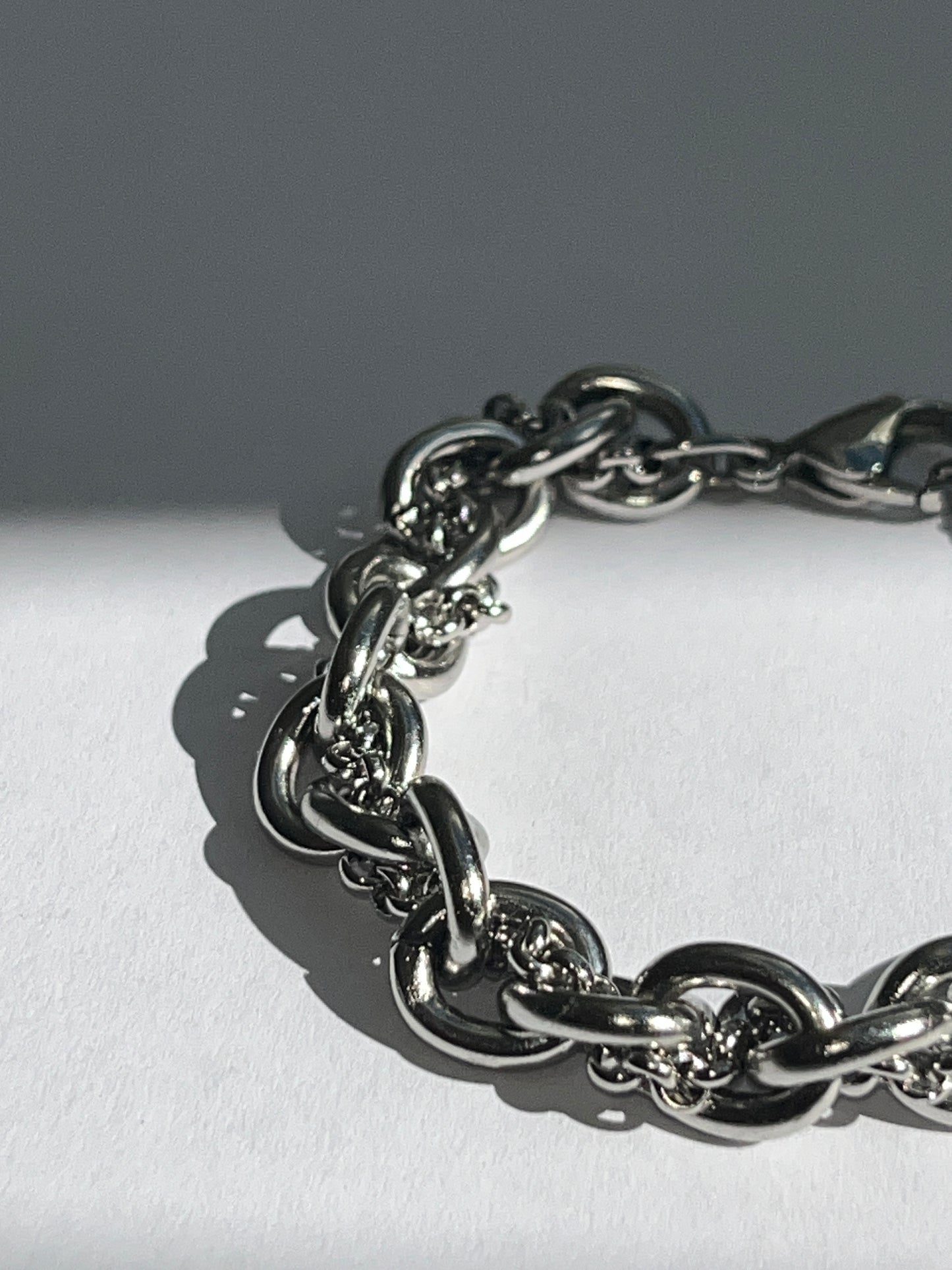 Extra closeup of chunky silver stainless steel intertwined chain bracelet showing texture and links.