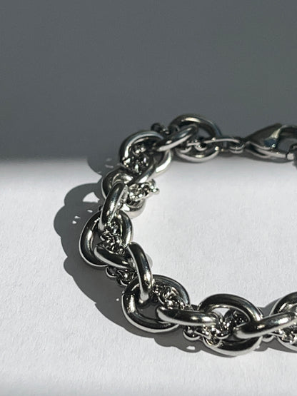 Extra closeup of chunky silver stainless steel intertwined chain bracelet showing texture and links.