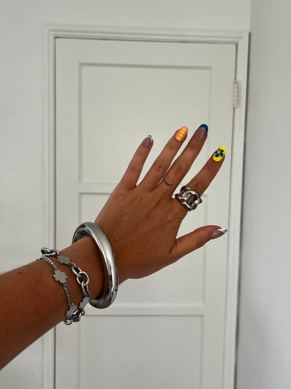 Angled view of THE CHUNKER ring with interlocked loops, high-polish stainless steel unisex statement piece.