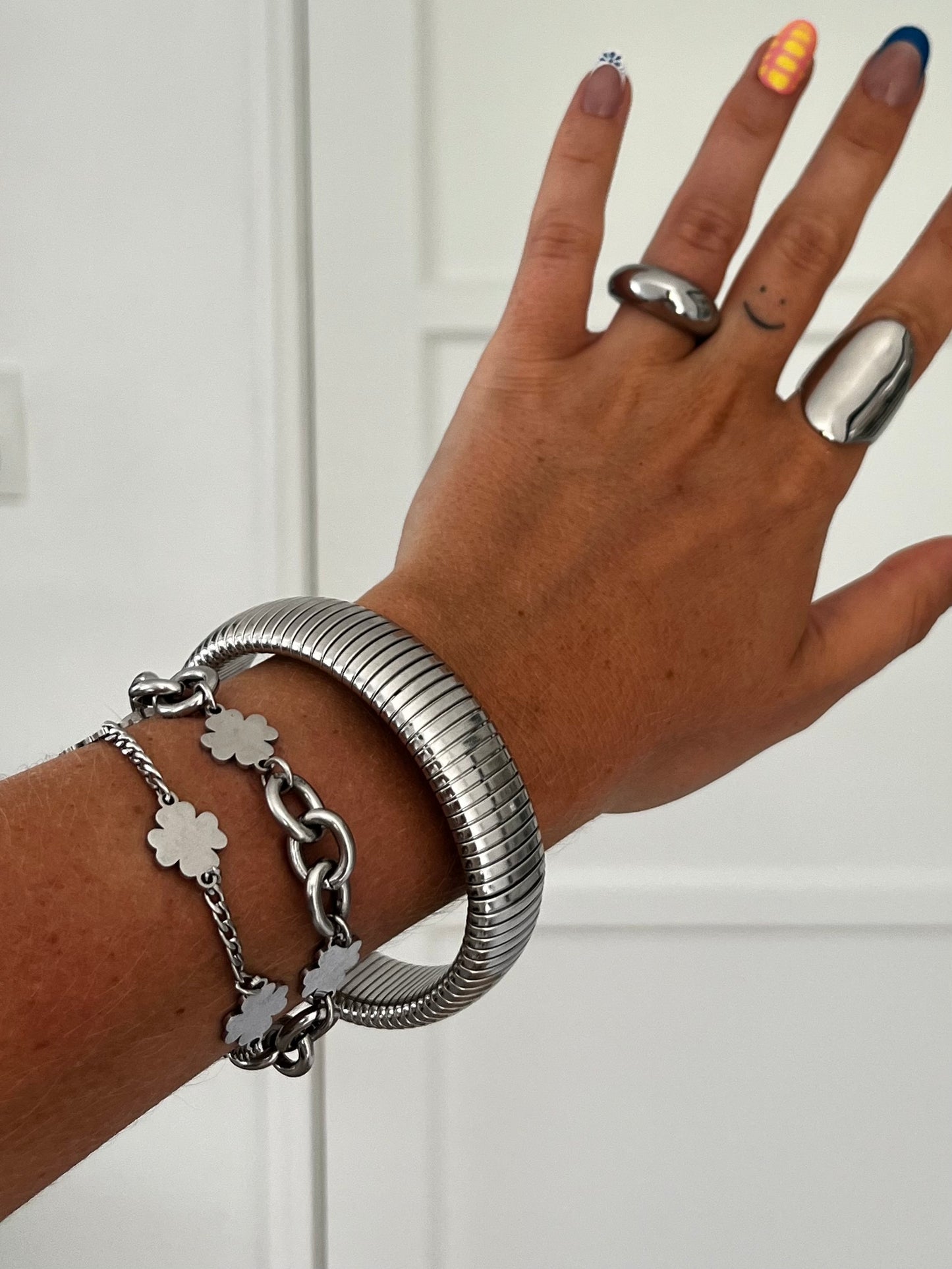 Side view of THE SPRING BANGLE showing coiled stainless steel design, polished unisex statement bracelet.