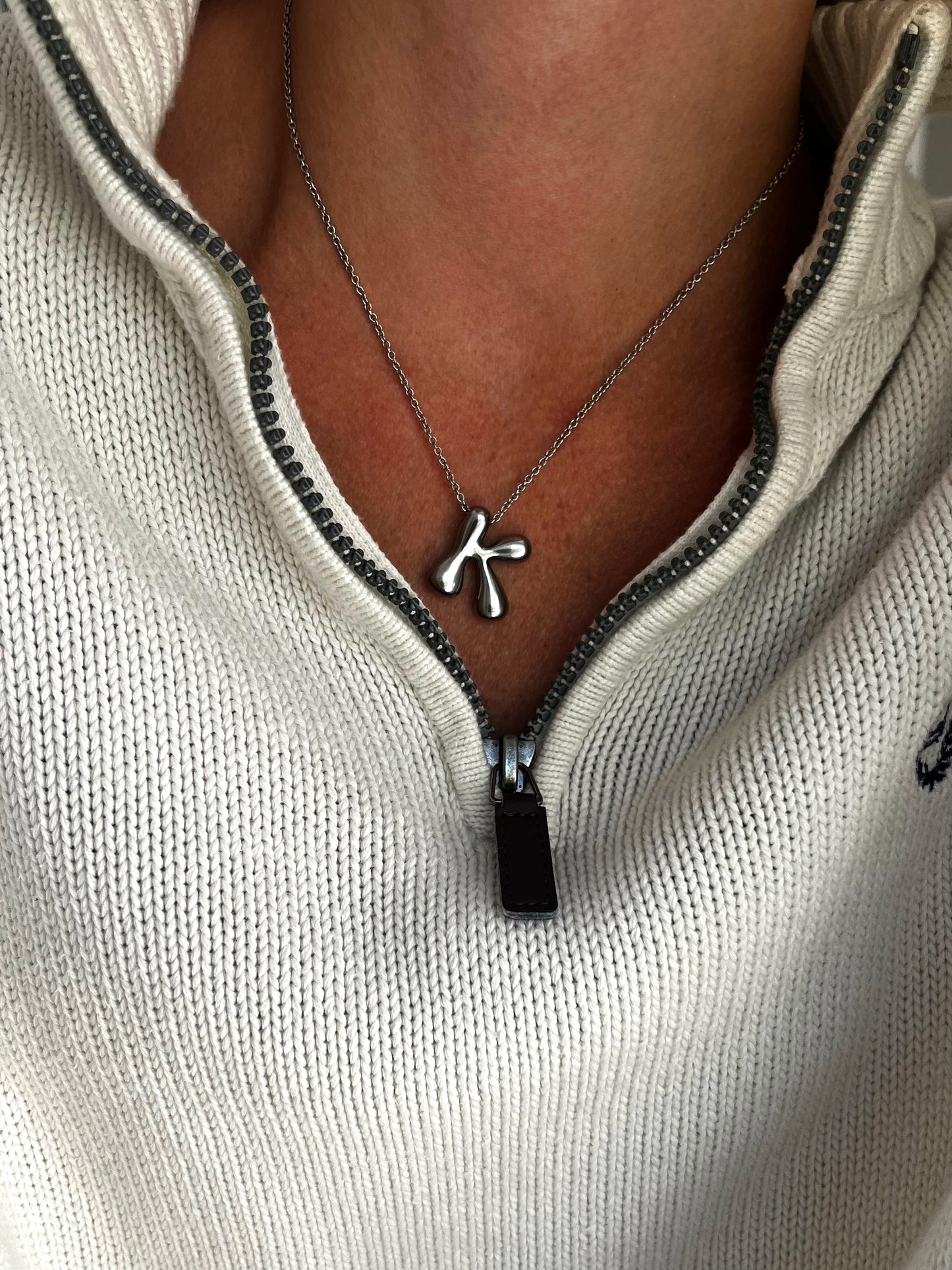 Necklace with a pendant worn by a person in a light-colored sweater.
